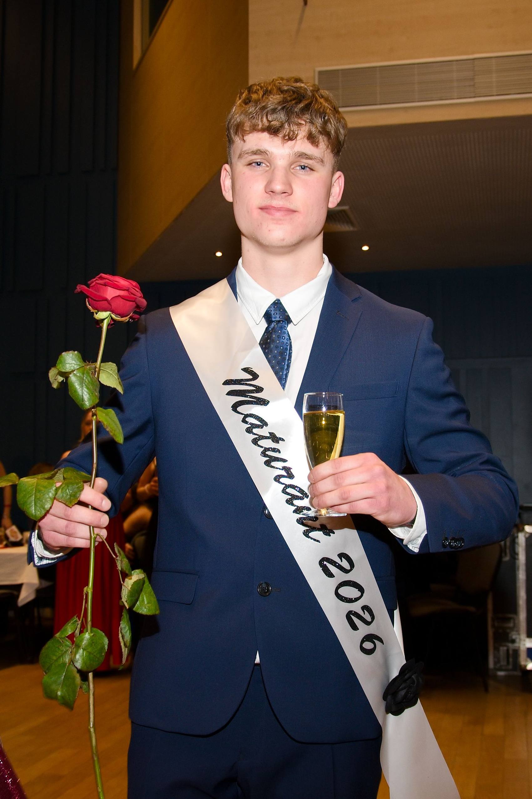 Maturant se šerpou Maturant 2026 a růží v ruce